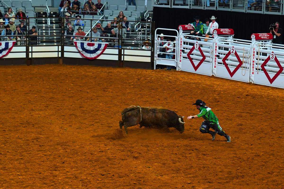 Bullfighter in green dodging a bull in a rodeo arena