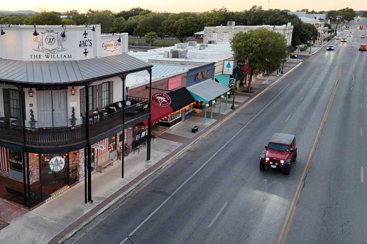 Twilight view of a quiet street with cars and lined 