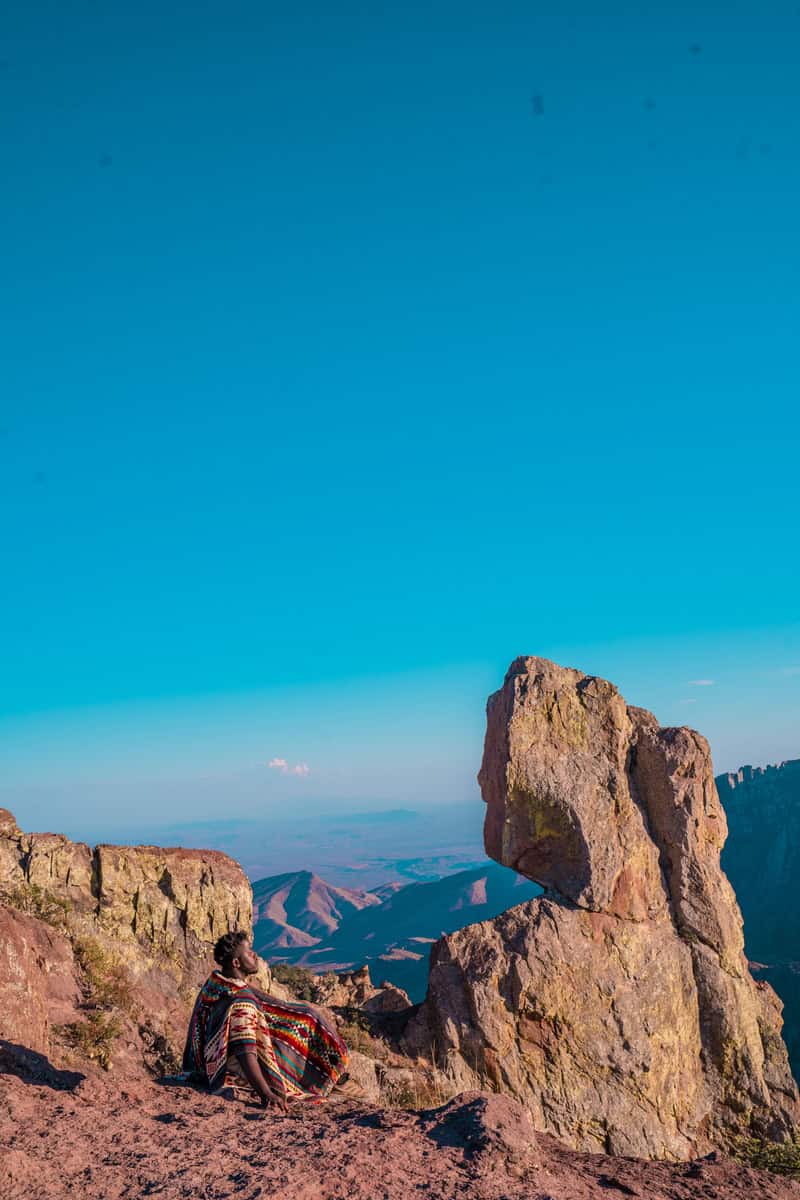 Person in colorful clothing sitting on a mountain ledge