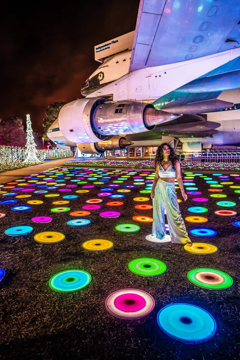 A person stands on a vibrant floor with colorful illuminated circles