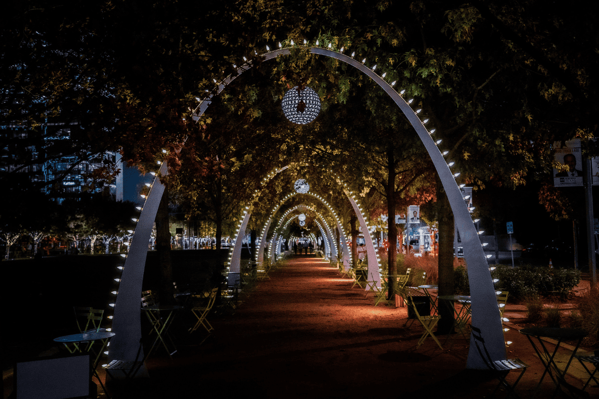 A tree-lined pathway with illuminated arches