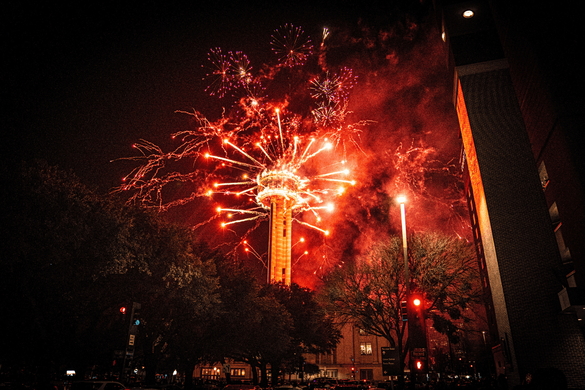 Fireworks erupting behind a tower at night with a vibrant display of lights.