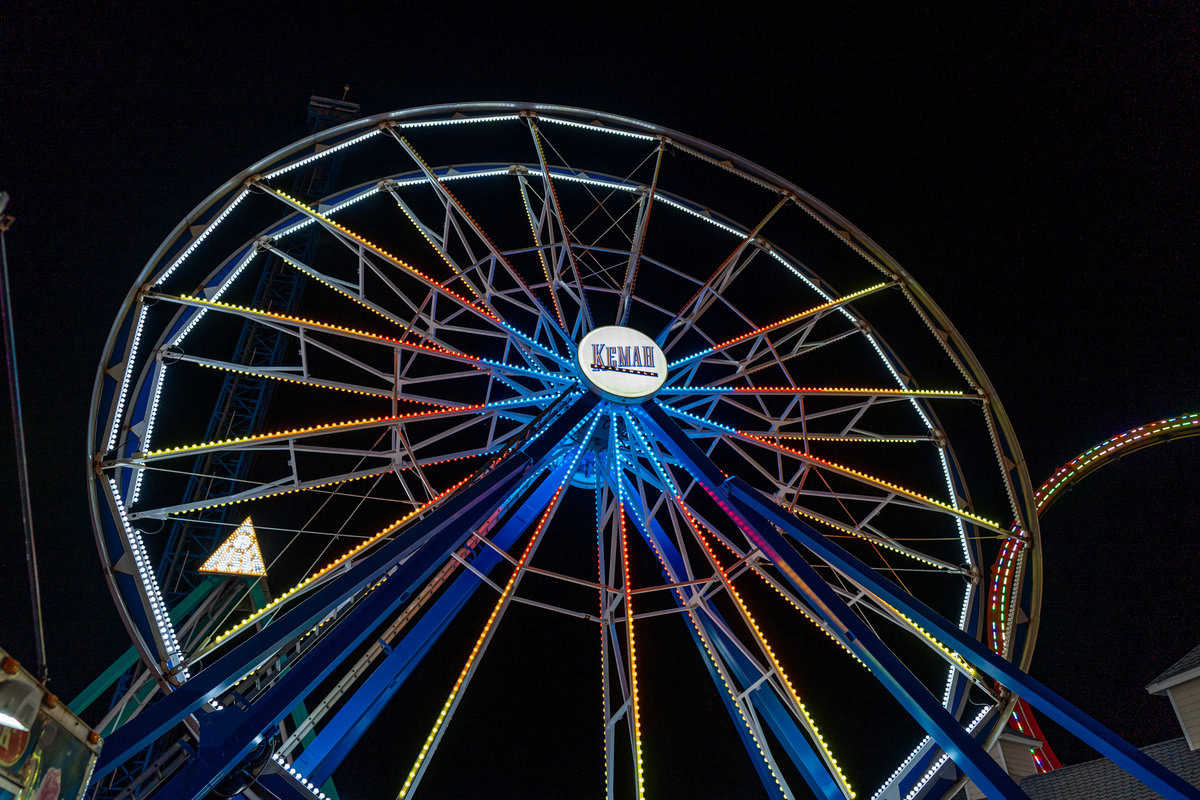 A brightly lit Ferris wheel at night with colorful lights and a clear sky.