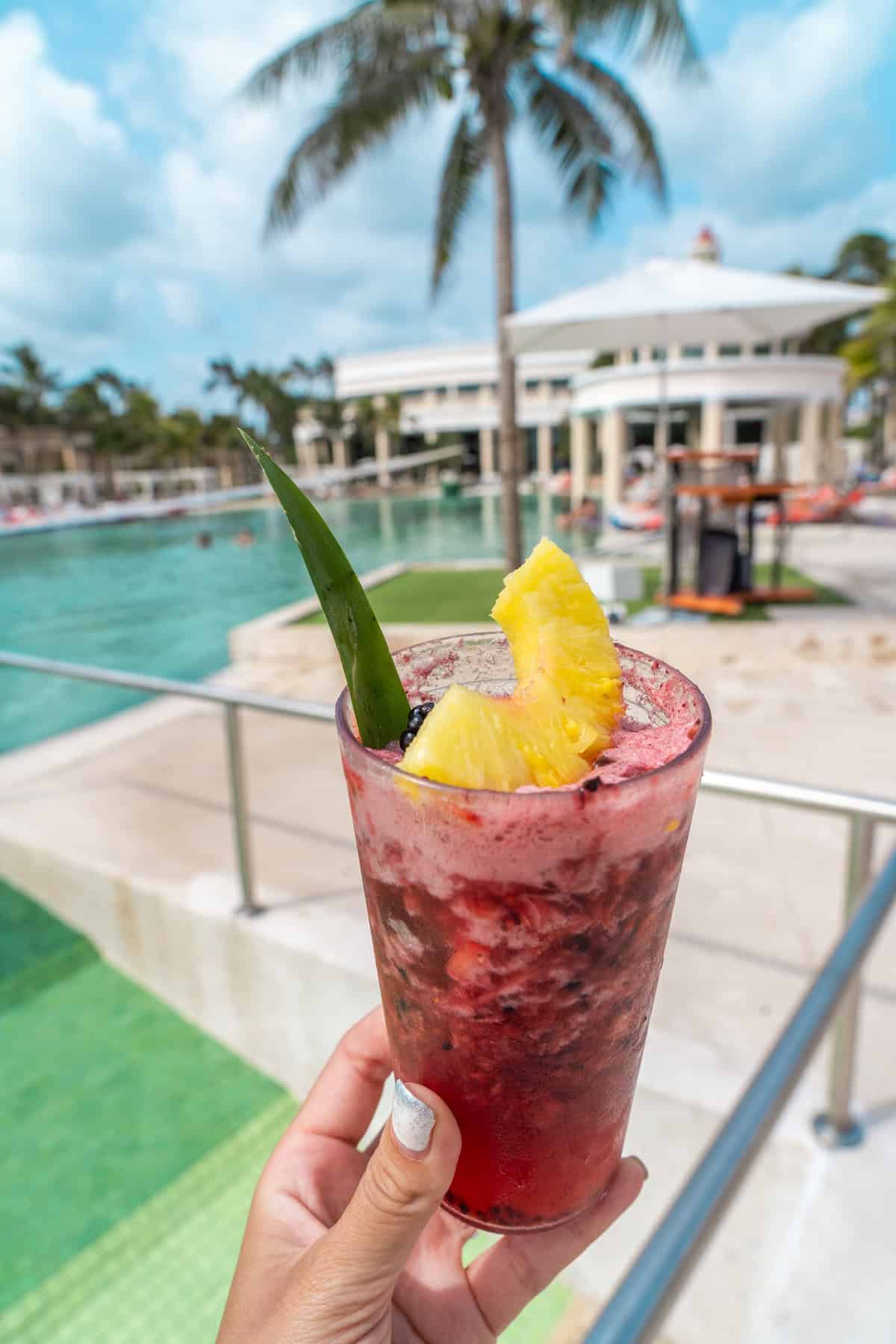 A hand holding a colorful cocktail