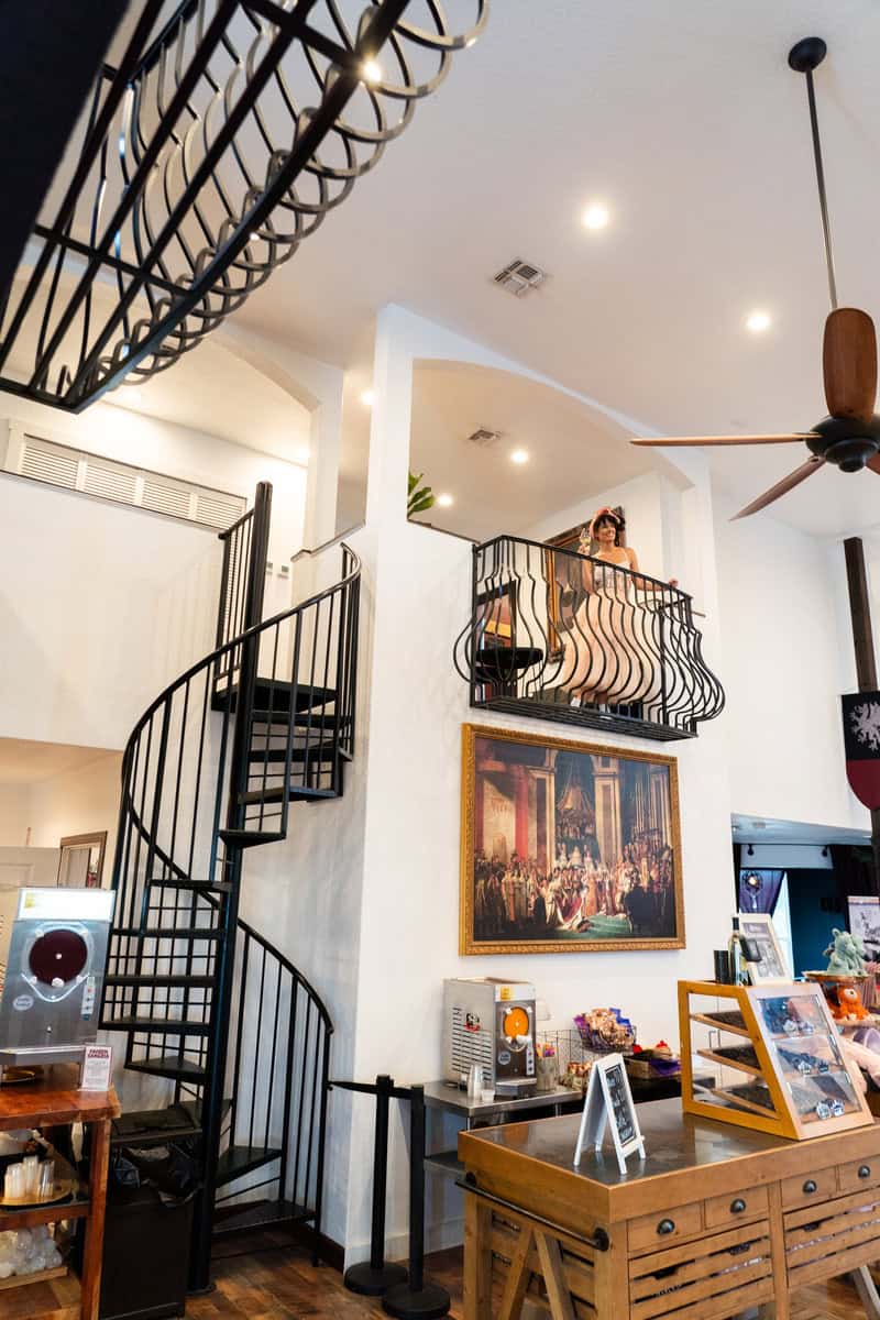 A stylish cafe interior featuring a spiral staircase, wooden furniture, and art