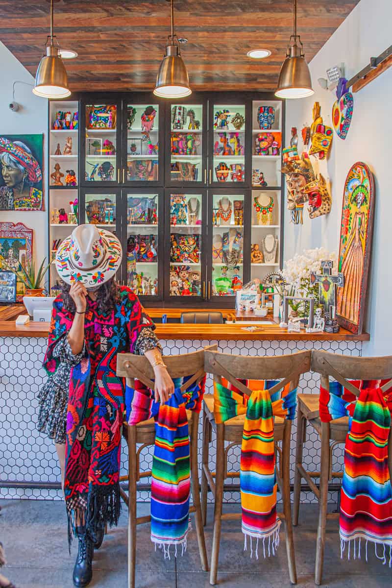 A woman in a vibrant poncho and decorative hat stands