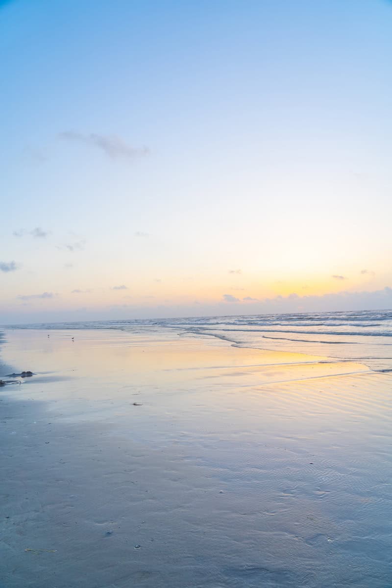 Calm beach scene at dawn with gentle waves lapping the shore