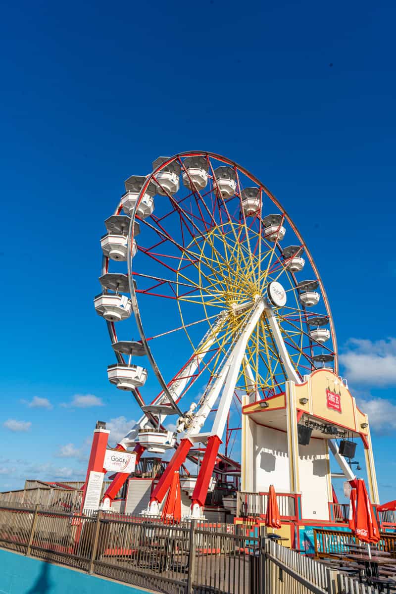 A colorful Ferris wheel stands tall against a blue sky