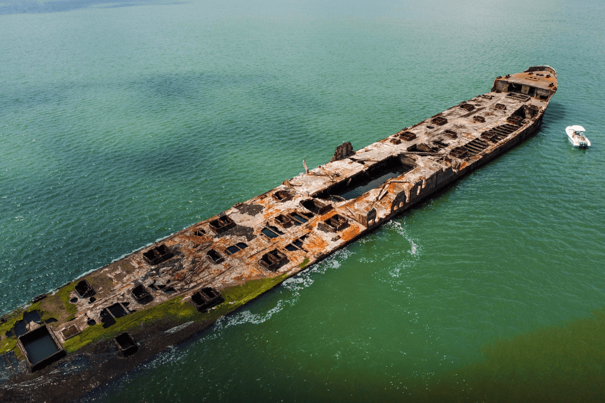 Aerial view of a rusted shipwreck in turquoise waters