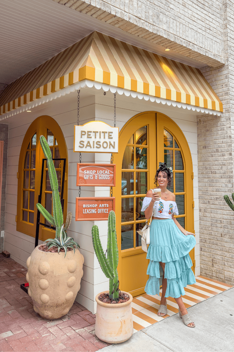 A woman stands in front of the colorful 'Petite Saison' shop