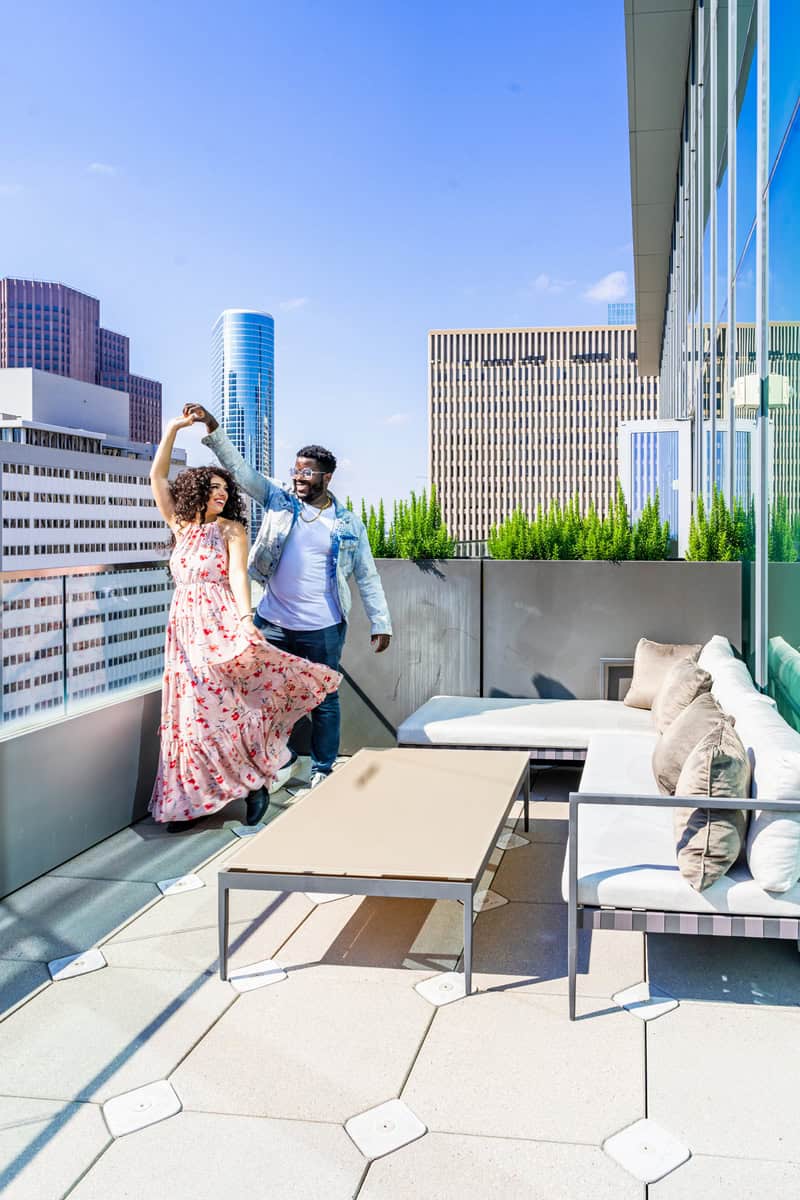 A couple dances joyfully on a rooftop terrace