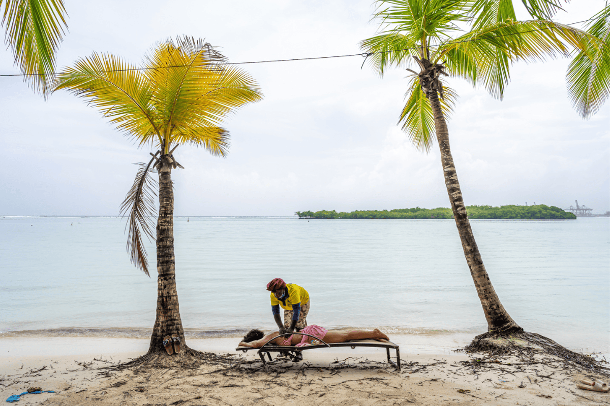 A woman receives a beach massage under palm trees