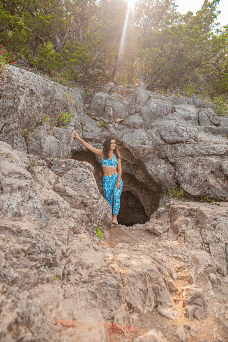 A woman in blue and white stands in a cave