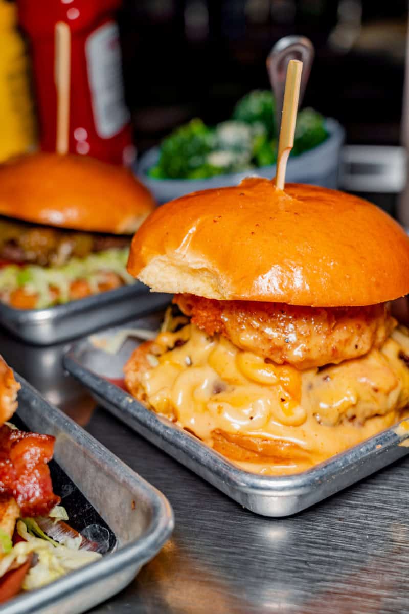 A close-up of a decadent burger with a crispy chicken patty
