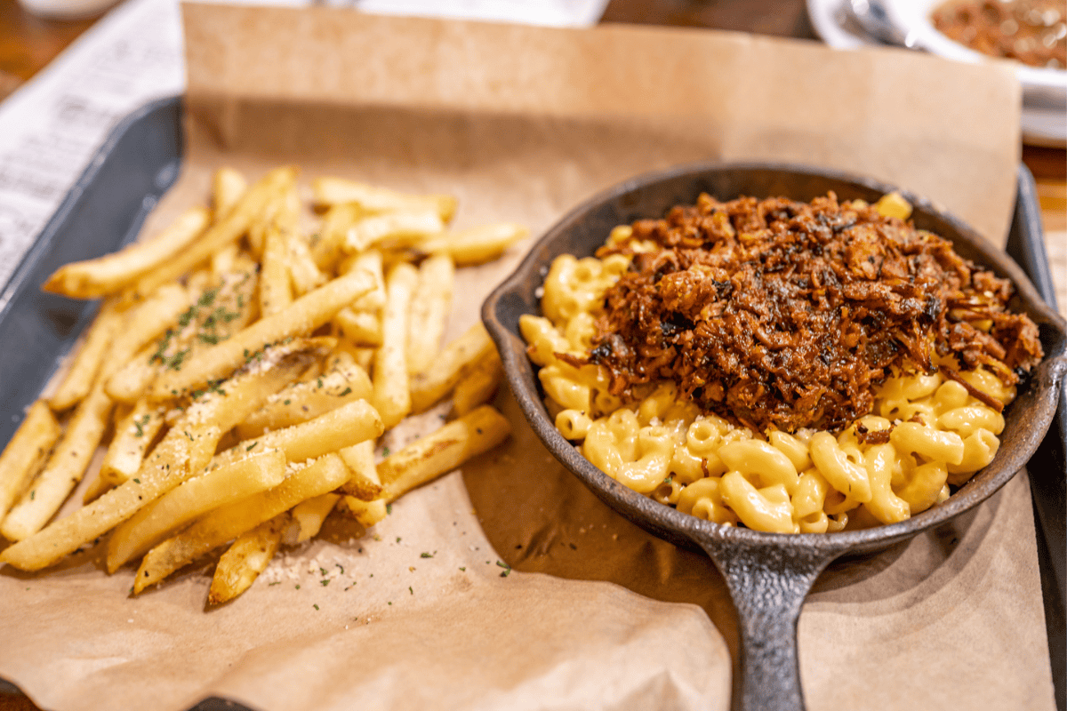 A cast iron skillet holds creamy macaroni topped with pulled beef