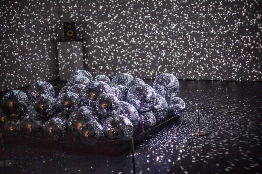 A cluster of reflective spheres on a dark floor