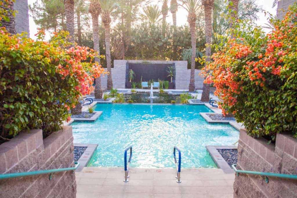 A serene pool surrounded by palm trees and vibrant flowers