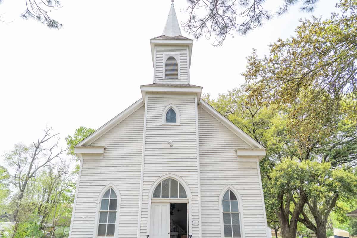 A quaint white chapel with a steeple and arched windows in Tomball Museum Center