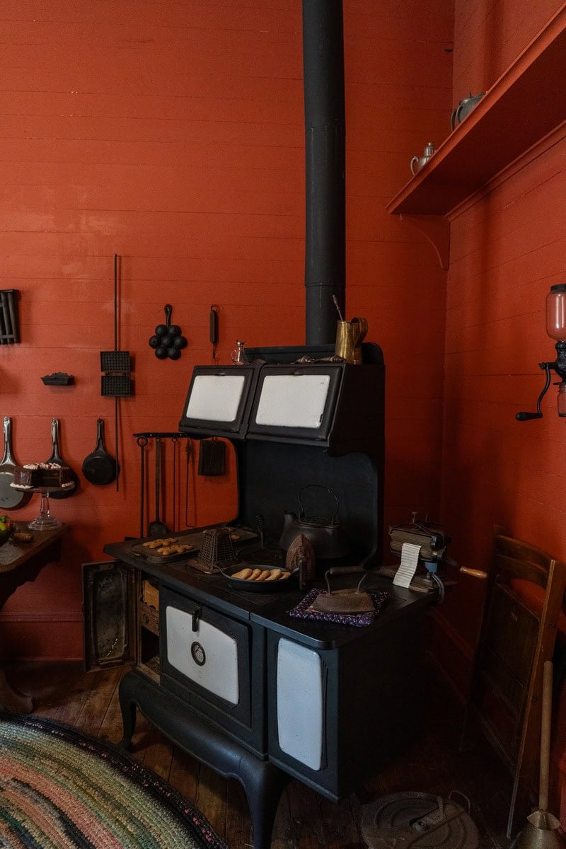 A vintage black stove with a chimney, cookies baking on top inside the Griffin House in Tomball Museum Center