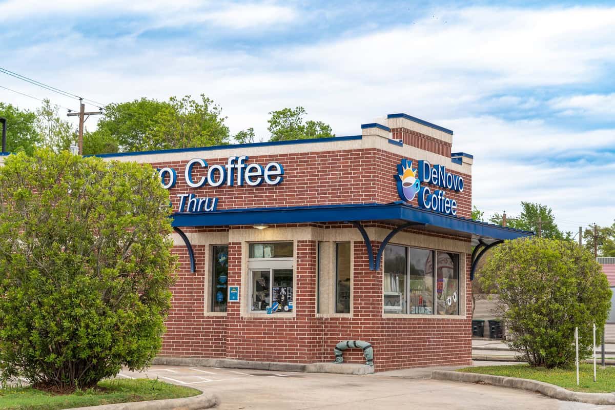 A brick coffee shop named "DeNovo Coffee," featuring a drive-thru window in tomball