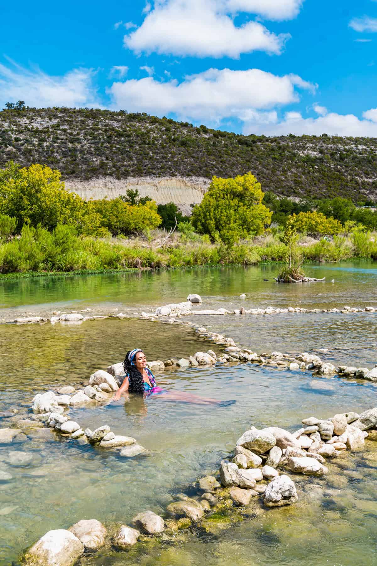 Jessica swims in a river with large rocks in South Llano River