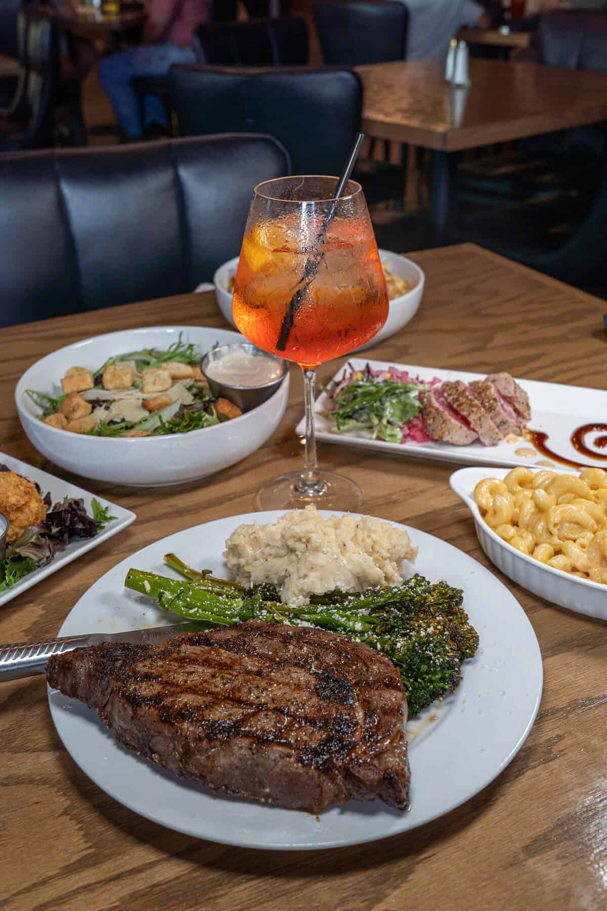 A table set with a juicy steak, fresh salad, and a refreshing drink