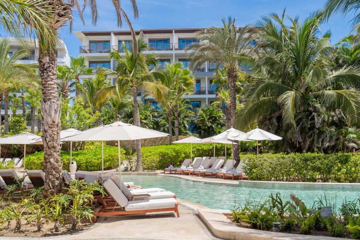 Pool loungers and palms around a resort pool at Conrad Punta de Mita.