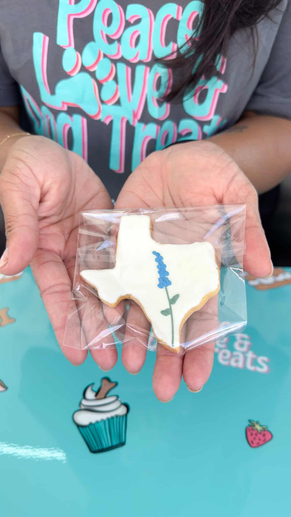 Someone holds a Texas-shaped cookie at the Tomball Farmers Market.