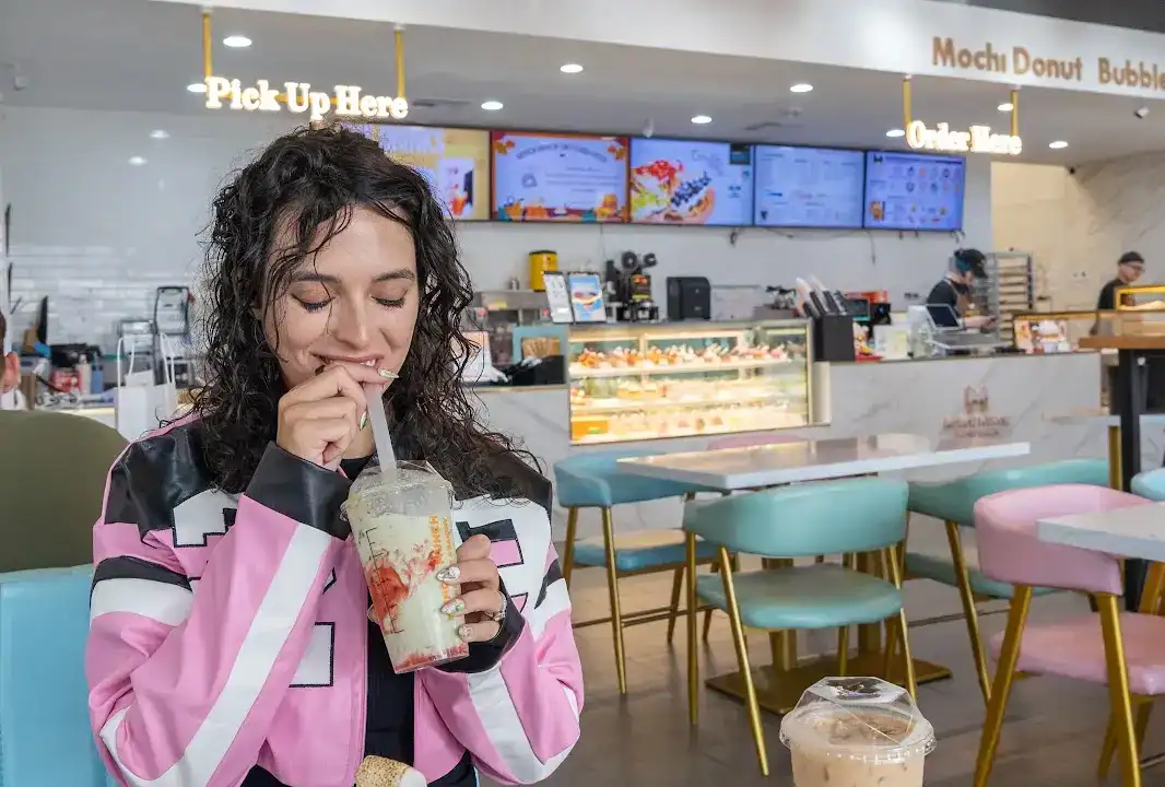 Jessica holding pastries and boba at MunchMunch Mochi Donut and Bakery