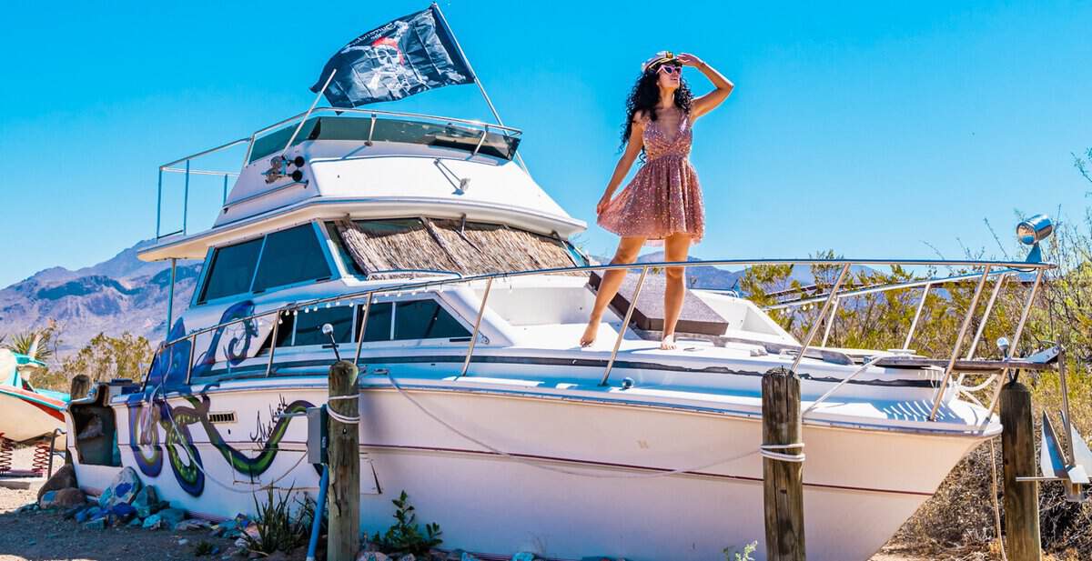 Woman standing on a vintage boat stay at Tin Valley Retro Rentals under a bright blue Big Bend sky